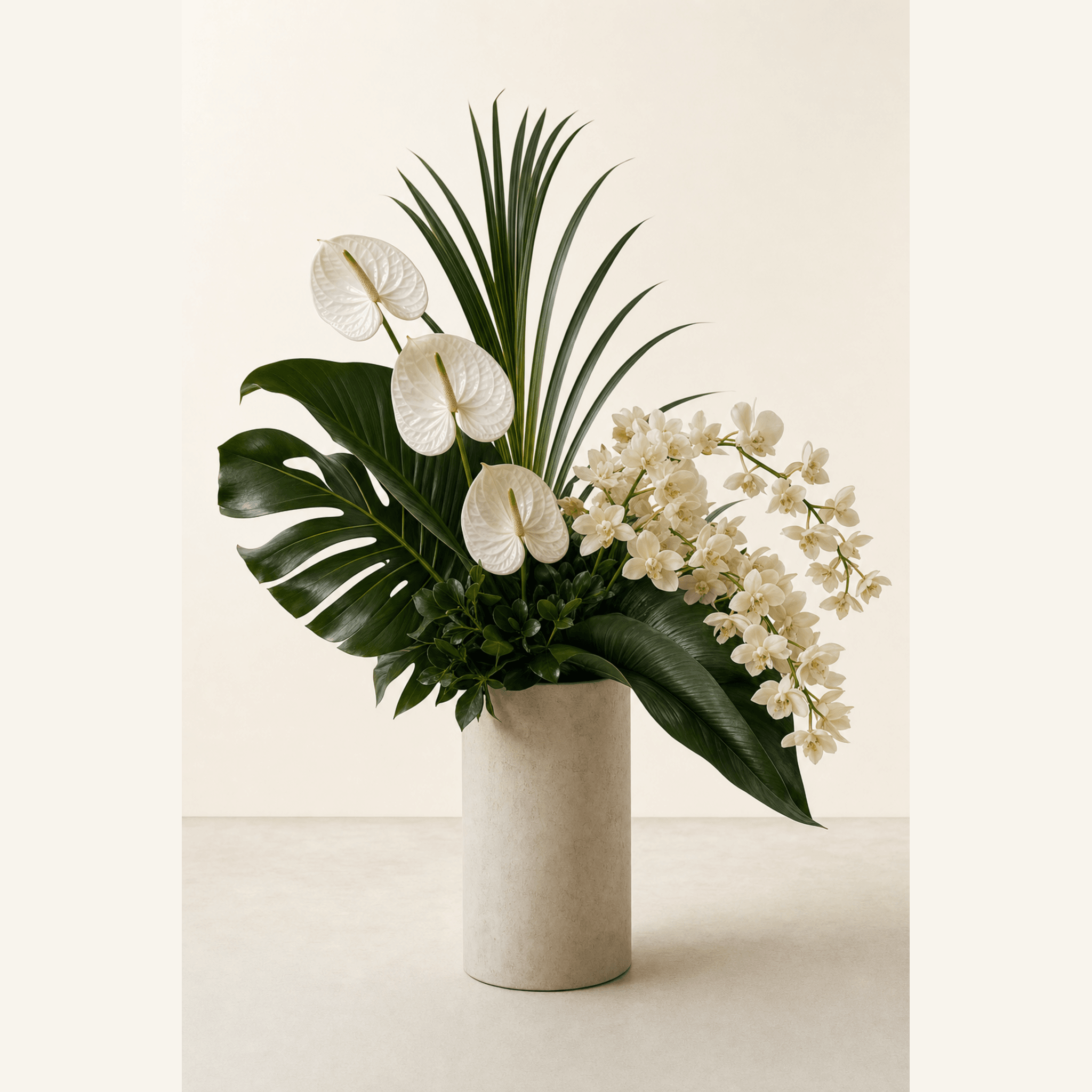 White anthuriums and cream orchids with tropical foliage in a tall stone cylinder vase