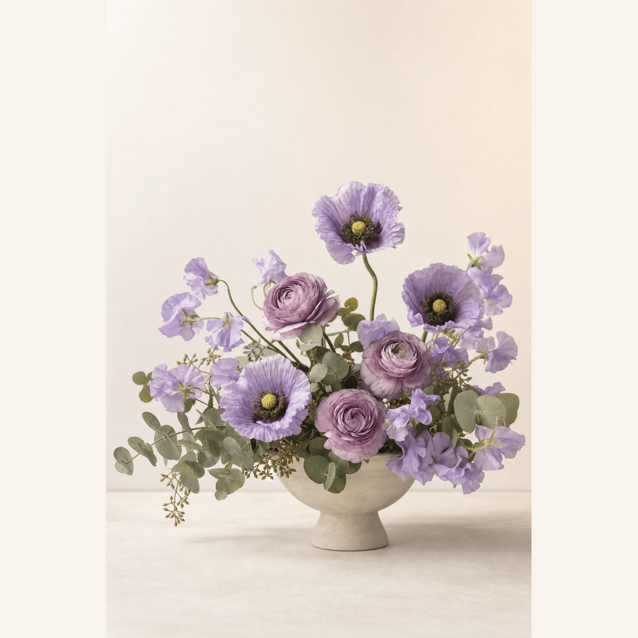 Lavender poppies, ranunculus, sweet peas and eucalyptus in a cream footed ceramic bowl