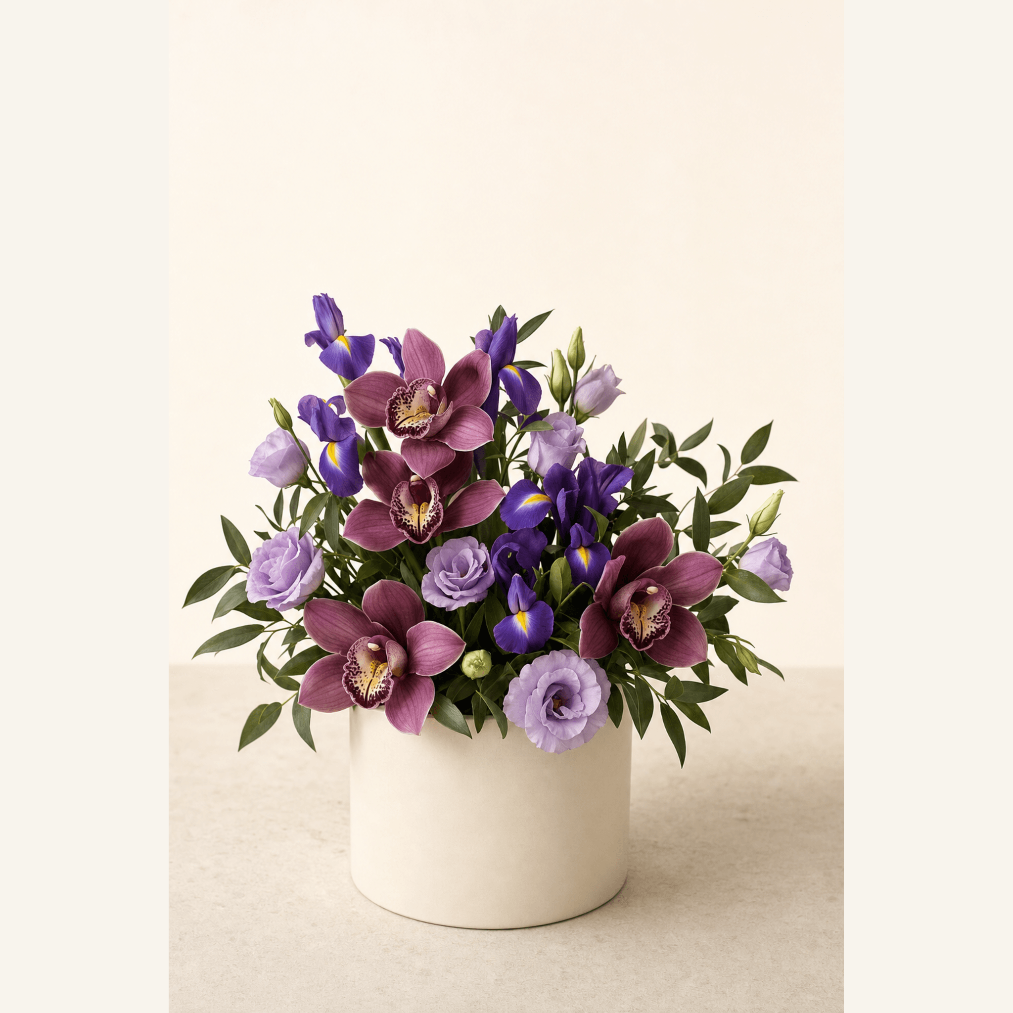 Purple cymbidium orchids, irises, and lavender lisianthus in a white ceramic pot