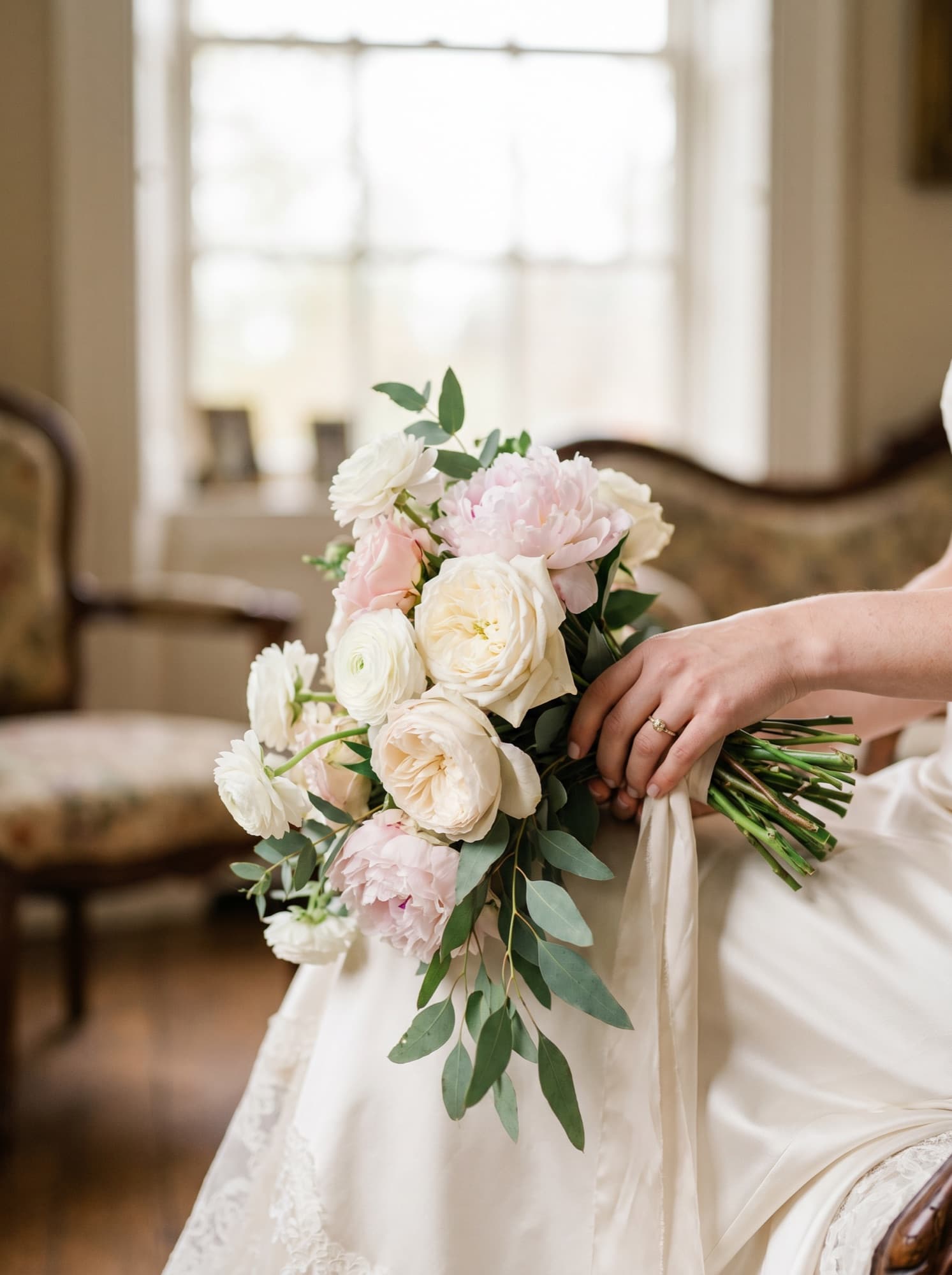 A bride holding an ivory and blush hand-tied bouquet